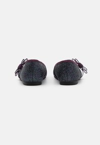 Glitzernde schwarze Ballerinas mit einer runden Zehe und einer Schleifenakzentuierung, die eine glatte Textur und einen niedrigen Absatz aufweisen.