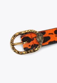 Pasek w panterkę z pomarańczowym i czarnym teksturowanym paskiem oraz złotą owalną klamrą ozdobioną dekoracyjnymi ćwiekami i motywem liścia.