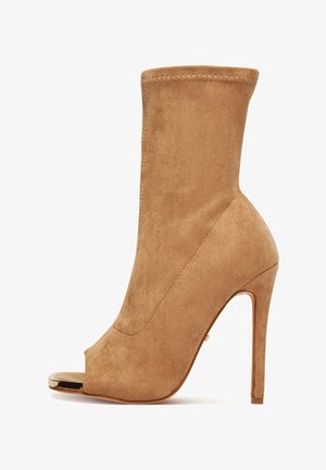 Beežist seemisnahast pahklakuking peep-toega, kõrge kontsaga, siledapinnaline ja metallilise aktsendiga varbaosas. Keha lähedane disain.