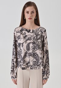 Blusa a maniche lunghe in tessuto rosa chiaro con motivo paisley nero. Collo arrotondato e vestibilità ampia, con polsini arricciati sulle maniche.