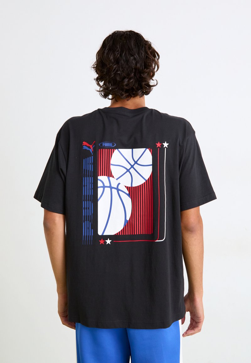 Sort bomulds T-shirt med et farverigt grafisk motiv af to basketballer med røde, blå og hvide detaljer, samt horisontale stribede detaljer på ryggen.