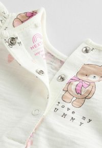 Body en coton blanc pour bébé avec un motif d'ourse, accents roses, fermetures à pression et texte indiquant "J'aime ma Maman" en dessous de l'illustration.