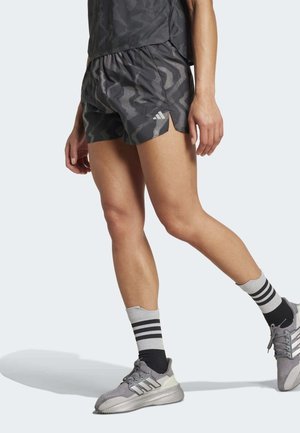 Zwart en grijs gemusterde sportshorts met een elastische tailleband, gecombineerd met grijze sneakers en zwart-gestreepte enkelsokken.