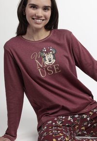 Top de manga larga color burdeos con un gráfico impreso en dorado de "Minnie Mouse" y un lazo de lunares, combinado con pantalones a juego con un patrón que presenta personajes de dibujos animados.