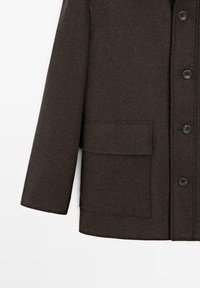 Cappotto marrone con motivo a spina di pesce, fronte con bottoni, taschino singolo sul petto e maniche lunghe. Tessuto strutturato e bottoni neri.