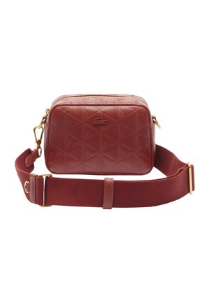 Sac bandoulière rectangulaire en cuir rouge avec motif embossé et logo crocodile, doté d'une large sangle en tissu réglable avec des éléments dorés.
