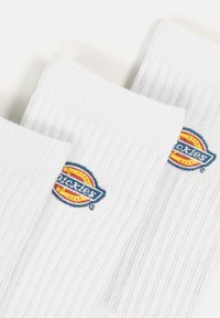 Baltas ribots zeķes ar zilu un dzeltenu izšūtu "Dickies" logo. Mīksta tekstūra un vidēja augstuma, piemērotas ikdienas valkāšanai.