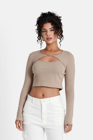 Beige gerippter Langarm-Crop-Top mit rundem Ausschnitt und einem Cut-Out-Detail an der Brust. Kombiniert mit weißen High-Waist-Cargohosen.