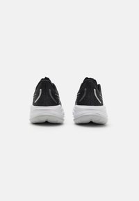Scarpe sportive nere con tomaia in rete traspirante, dotate di suole bianche e dettagli riflettenti. Design classico adatto a diverse attività.