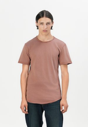 T-shirt marron à manches courtes avec un col rond, en tissu doux, présentant un ourlet légèrement courbé et des détails de couture minimalistes.