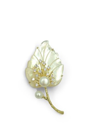 Spilla d'oro a forma di foglia con accenti di perle e pietre preziose trasparenti disposte intorno a una perla centrale su sfondo bianco.