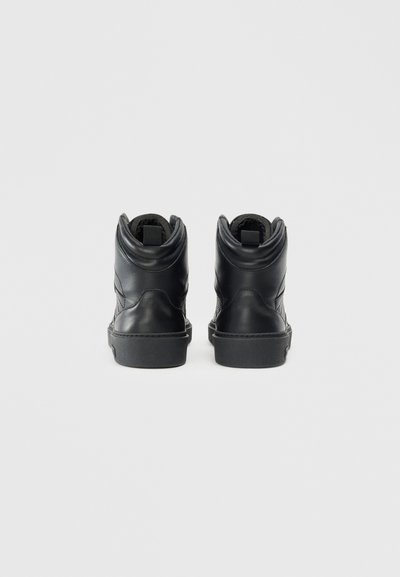 Botine negre din piele cu un finisaj neted, cu guler căptușit și un design texturat pe lateral. Talpă din cauciuc cu vârf rotunjit și bucla de prindere pe spate.