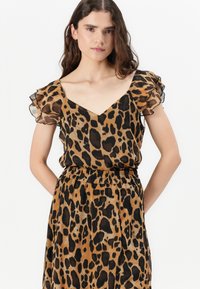Leopardmønstret kjole i brunt og sort, med V-hals, korte flæsermer og elastisk talje for en afslappet pasform.