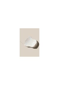 Plat en céramique blanc, de forme irrégulière, avec un bord texturé et ondulé. Surface lisse avec un subtil éclat. Posé sur un fond beige clair.