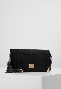 Borsa nera imbottita in suede con una piastra dorata e dettagli con frange. Dotata di una tracolla a catena e una texture liscia.