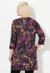Lange tuniek in een paisleypatroon, met tinten paars, zwart en goud. Gemaakt van een lichtgewicht, gestructureerde stof. Driekwart mouwen.