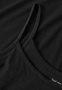 Svart bomullstanktop med tunna axelband, rundad halsringning och slät tygstruktur. Synliga sömnadsdetaljer längs halsringningen.