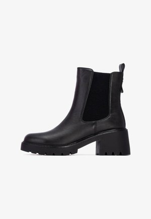 Botas Chelsea negras con un upper de cuero liso, paneles laterales elásticos texturizados, un tacón grueso y una pestaña en la parte posterior.