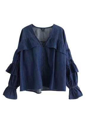 Sininen farkkupaita, jossa on röyhelökoristeet hihoissa ja rinnassa, V-pääntie, etupainikkeet ja elastiset hihansuut.