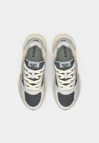 Gray and silver athletic shoes with mesh and synthetic materials, featuring white laces and yellow accents on the sides and heel.