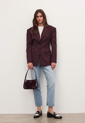 Bordeaux oversized blazer med strukturerede skuldre, parret med lyseblå lige ben jeans. Bærer en blank bordeaux håndtaske og har sorte loafers på.