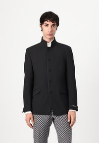 Black tailored blazer with a high collar, button closure, and side pockets. Smooth texture with contrasting details.