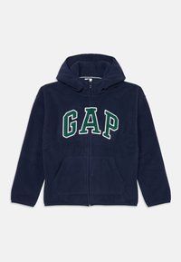 Navy blue fleece hoodie with front zip, large "GAP" logo in white and green, two front pockets, and a drawstring hood.