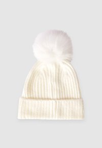 Biała prążkowana zimowa czapka z podwiniętym brzegiem i dużym puszystym pomponem na górze, umieszczona na jasnoszarym tle.