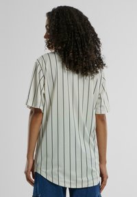 Lysegrønn kortermet skjorte med svarte vertikale striper, med en avslappet passform og rund hemline, laget av et mykt, teksturert stoff.