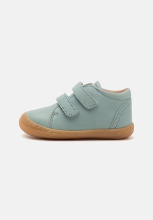 Chaussure en cuir bleu clair avec un design montante, dotée de deux bandes Velcro, d'une semelle en caoutchouc flexible et de détails cousus.