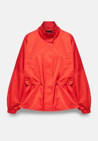 Veste légère rouge vif avec col montant, poignets élastiques et détails froncés à la taille, présentée sur un fond uni.