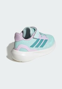 Αθλητικό παπούτσι σε ανοιχτό τυρκουάζ με μοβ λεπτομέρειες, επάνω μέρος από διχτυωτό υλικό και λευκή μεσαία σόλα. Διαθέτει λουράκι με βέλκρο και τρεις σκούρες τυρκουάζ ρίγες στο πλάι.