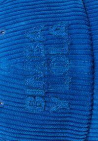 Tela de pana azul con texto bordado en relieve que dice "BMW MOTORRAD" en hilo azul a juego.