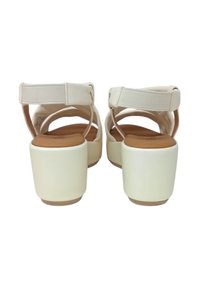 Sandali platform bianchi con tacco robusto, caratterizzati da una superficie liscia e da cinturini elastici per il supporto. Soletta color marrone chiaro con design minimalista.