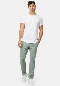 Camiseta de algodón blanca combinada con pantalones verdes claros, con un corte ajustado y un diseño sencillo. Completado con zapatillas blancas para un look casual.
