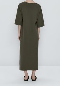 Longue robe vert olive à manches courtes, coupe décontractée, fentes latérales et col rond, en tissu lisse.