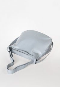 Lichtgrijze leren tas met een gladde textuur, rechthoekige vorm, verstelbare schouderriem en een ritssluiting langs de onderrand.