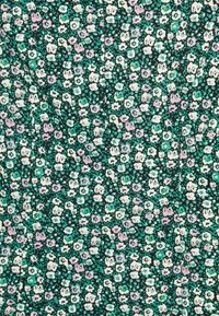 Le tissu à motifs floraux présente un fond vert foncé orné de petites fleurs blanches, roses et turquoise éparpillées, créant un motif texturé.