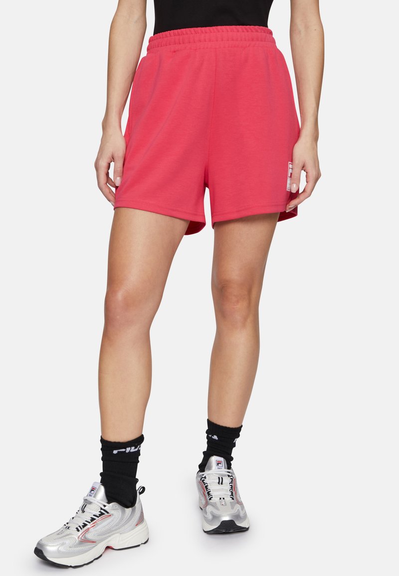 Pantalones cortos deportivos rosa con cinturilla elástica, hechos de una tela suave. Cuenta con bolsillos laterales y un detalle de logo en el muslo izquierdo.