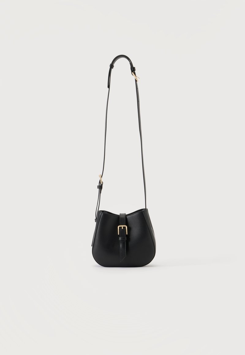 Μαύρη τσάντα crossbody από δέρμα με στρογγυλεμένο σχήμα και χρυσή πόρπη μπροστά, που κρέμεται από λεπτό, ρυθμιζόμενο ιμάντα.
