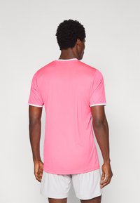 Ροζ αθλητική μπλούζα με κοντά μανίκια, διαθέτει λευκή επένδυση γύρω από το γιακά και τα μανίκια, κατασκευασμένη από ελαφρύ, λείο ύφασμα.