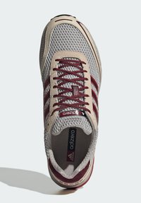 Γκρι και μαρουν Adidas Adizero αθλητικό παπούτσι με επάνω μέρος από δίχτυ, σουέτ λεπτομέρειες και κόκκινα κορδόνια, φαίνεται από πάνω.