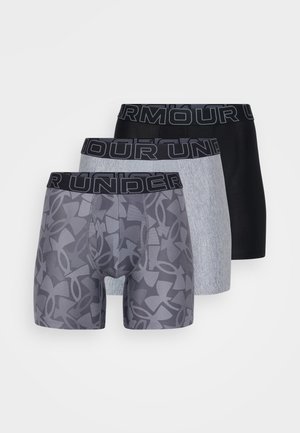 Trois paires de boxers : une grise avec un motif géométrique, une noire uni et une gris clair, toutes avec une ceinture "UNDER ARMOUR" noire.