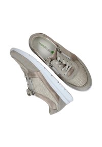 Beige sneakers met een gestructureerde bovenkant, inclusief gladde en ribbelige panelen. Voorzien van een witte zool, veters en een ritssluiting aan de zijkant.