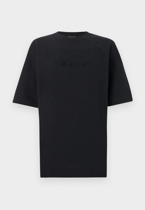 Czarny T-shirt z krótkim rękawem i zaokrąglonym dekoltem, na środku klatki piersiowej znajduje się czarny wypukły napis „NIKE” na jednolitym tle.