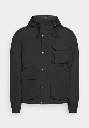 Giacca nera realizzata in materiale leggero, con cappuccio, bottoni a pressione, multiple tasche frontali e polsi elasticizzati. Texture liscia.