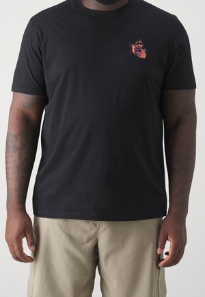 T-shirt in cotone nero con maniche corte, con una piccola grafica di una farfalla viola e arancione sul lato sinistro del petto.