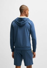 Blue hoodie made of soft fabric, featuring a drawstring hood, ribbed cuffs, and side accents. Paired with matching shorts.