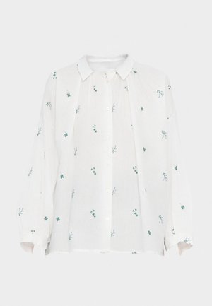 Chemise en lin blanc avec un devant à boutons. Présente des broderies florales vertes et bleues, des manches longues et un col pointu. Coupe décontractée.