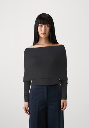 Black off-the-shoulder top with long sleeves, made of soft fabric. Features a straight hem and smooth texture, paired with navy trousers.